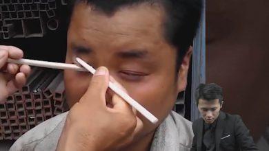 Уличный китайский фокусник достает из глаз червей